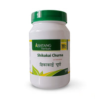 White container of Shikakai Churna with green lid and Ashtang Herbals branding on a white background